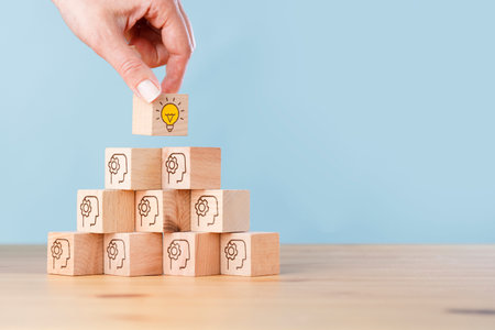 Woman hand picked wooden cube block with head human symbol and light bulb icon. Creative idea and...