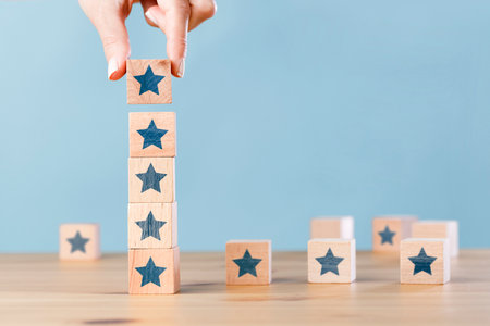 Woman hand building wood block cubes stacking on top with star shape. customer experience conceptの写真素材