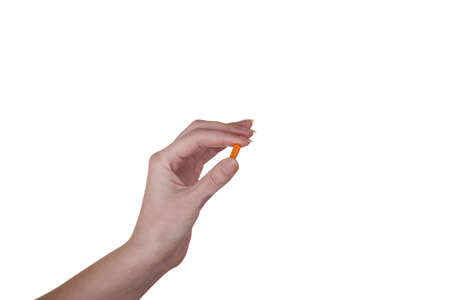 Hand holding an orange capsule isolated on white background macro studio shotの写真素材