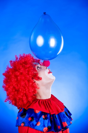 Smiling clown in studio shot on blue backgroundの写真素材
