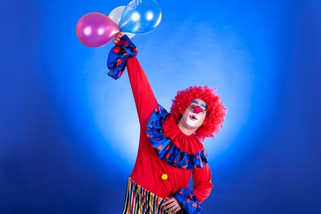 Smiling clown in studio shot on blue backgroundの写真素材
