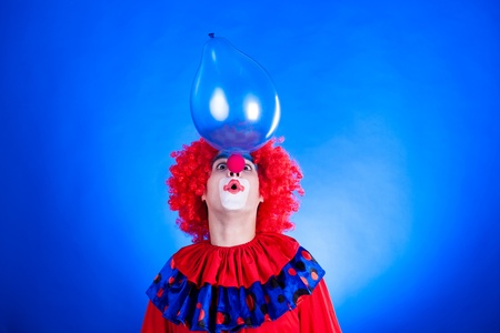 Smiling clown in studio shot on blue backgroundの写真素材