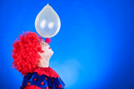 Smiling clown in studio shot on blue backgroundの写真素材