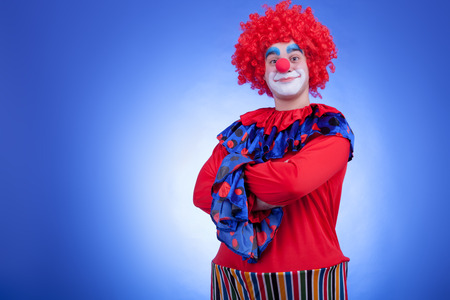 Smiling clown man in red costume on blue backgroundの写真素材