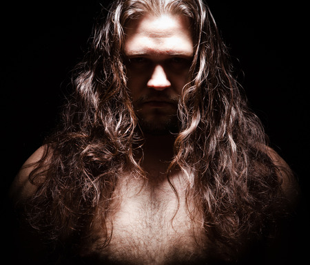 Angry men with long hairs on black background. Angry issues. Negative emotions. Big strong guy with long hairs on black bacground. Fear and expressionの写真素材