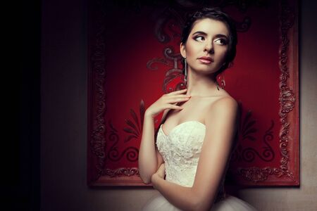 Gorgeous bride in wedding dress in vintage interior. Studio lights shooting. Retro red walls. Happy young bride. Wedding dayの写真素材