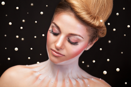 Woman surrounded by pearls in surrealistic concept photo. Studio shooting. Conceptual photographyの写真素材