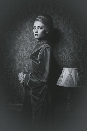 Woman in old style clothes in vintage interior. Retro luxury residence. retro dress. black and white imageの写真素材
