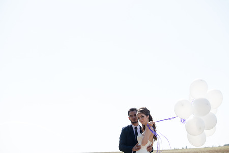 Girl in wedding dress and husbad with ballons in hands. Ballons at the skyの写真素材