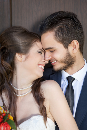 Laughing young bride and happy groom looking at her on wooden backgroundの写真素材