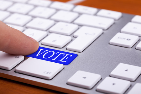 Finger pressing on vote blue button on keyboard. Online electionsの写真素材