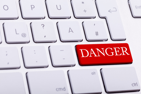 Alluminium keyboard with DANGER word written on red button close up photoの写真素材