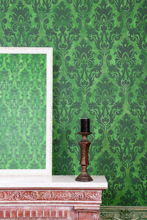 Old vintage mirrod in woden frame on chimney on green vintage pattern backgroundの写真素材