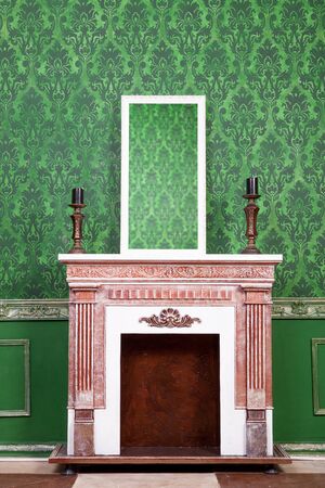 Old vintage mirrod in woden frame on chimney on green vintage pattern backgroundの写真素材