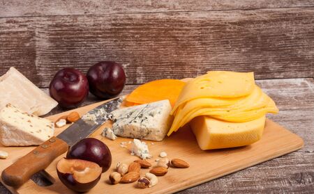 Different type of cheese and nuts on vintage wooden background in studio photoの写真素材