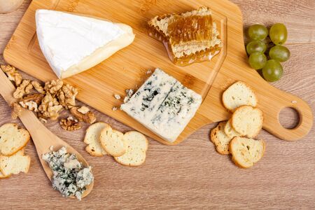 Overtop view on plate with nuts, cheese, grapes and crackers on vintage wooden background in studio photo. Healthy lifestyleの写真素材
