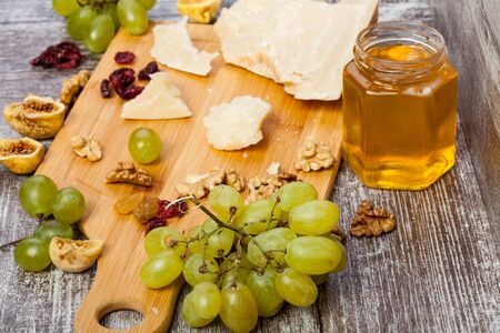 Honey, nuts, fruits and cheese on wooden background in studio photo. Healthy lifestyle. On top viewの写真素材