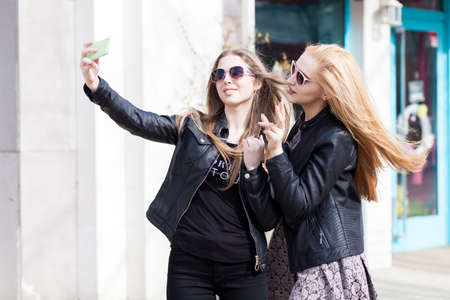 Girls making a selfie with the cellphone outside. Lifestyleの写真素材
