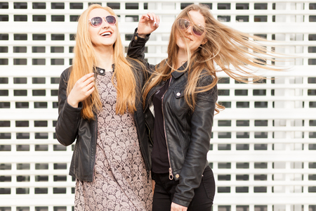 Best friends in sunglasess laughing on cell type industrial background. Fashion and lifestyleの写真素材