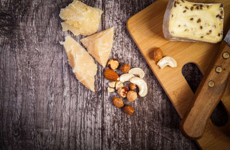 Different type of cheese and nuts on wooden background in close up photo. Copyspace availableの写真素材