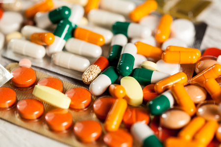 Many drugs and pills lying on table with blured background in close up photoの写真素材
