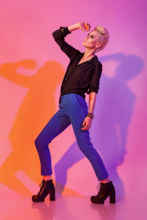 Woman with stylinsh haircut posing on pink background with colored shadows. Studio image. Fashion modelの写真素材