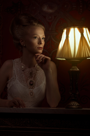 Woman in victorian style and vintage room with lamp beside her. Victorian romantic elegance femaleの写真素材
