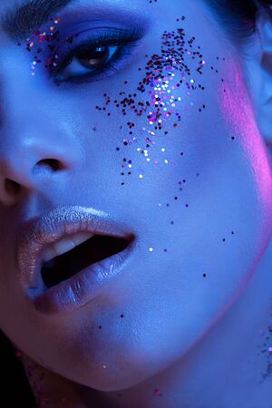 High end beauty image of girl covered in glitter in blue fashion light. Studio photo. Creative colorful make upの写真素材