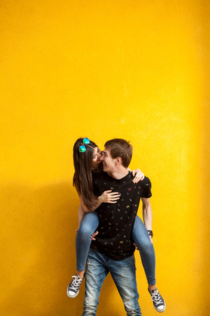 Couple laughing and having fun. Shot on yellow wallの写真素材