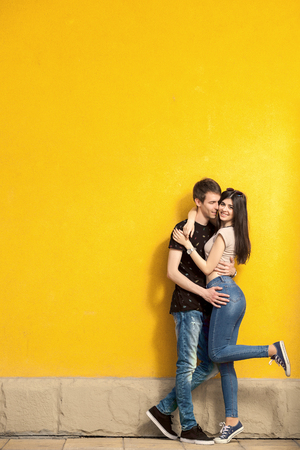 Smiling happy couple on yellow wall posing at the cameraの写真素材
