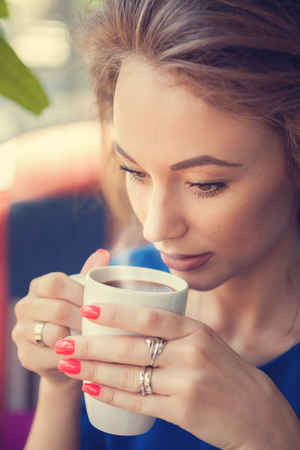 Woman from a cup of coffee with steam in close up portrait photo. Soft focus and blurred backgroundの写真素材