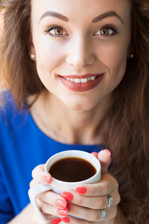 Woman smiling with a cup of coffee in hands. Soft focus imageの写真素材