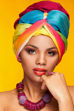 Young woman in ethnical afro american turban on yellow background in studioの写真素材