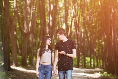 Couple walking and smiling each other with a soft light leack from above in the forest. Happines and activity in twoの写真素材