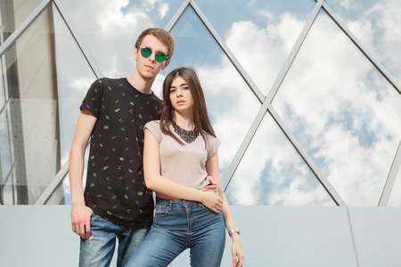 Happy cool looking couple in jeans in front of office building looking in the cameraの写真素材