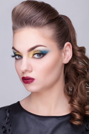 Girl with green and yellow make up on gray background in studio photo. Beauty portraitの写真素材