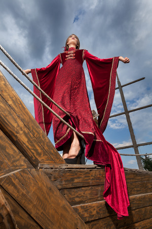 Woman in vintage clothes on a boat with dramatic sky on backgroundの写真素材