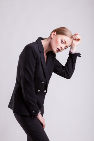 Beautiful model in business suit on gray background in studio photo. Fashion business styleの写真素材