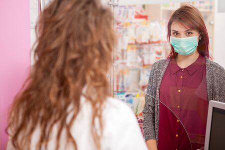 Client in pharmacy wearing a mask. Healthcare businessの写真素材