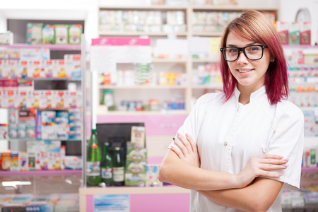Young pharmacist in glasses inside a pharmacy looking at camera and smilingの写真素材