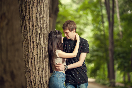 Couple embracing each other next to a tree in the forest. Warm weather. Family quality timeの写真素材