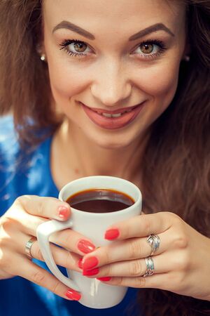 Smiling woman drinking coffe and looking up Beautiful young woman. Coffe loversの写真素材