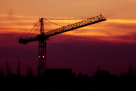 Vibrant sunset with crane silhouette in frame. Industry and constructionの写真素材