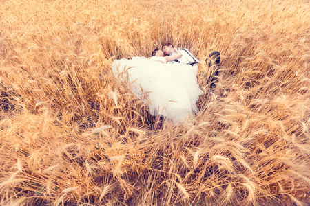 Happy bride and groom lying in a wheat field. Wedding photographyの写真素材