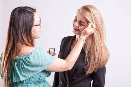 Make up artist applying make up on fashion model in studio photoの写真素材