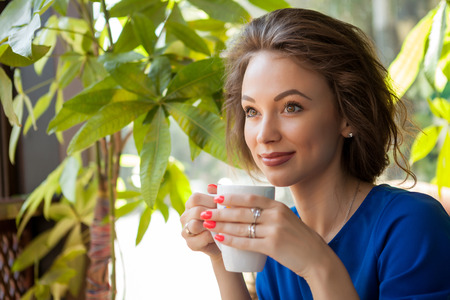 Beautiful young woman drinking coffe in a coffee shop. Beautiful young woman. Coffe loversの写真素材