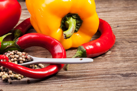 Spicy and sweet pepper on wooden background in studio photo