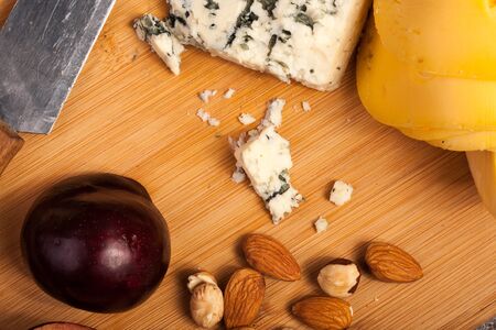 Nuts, cheese and fruits on wooden background in studio photoの写真素材