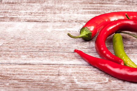 Spicy Red and green pepper on wooden background in studio photoの写真素材