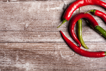 Red and green spicy pepper on wooden background in studio photoの写真素材